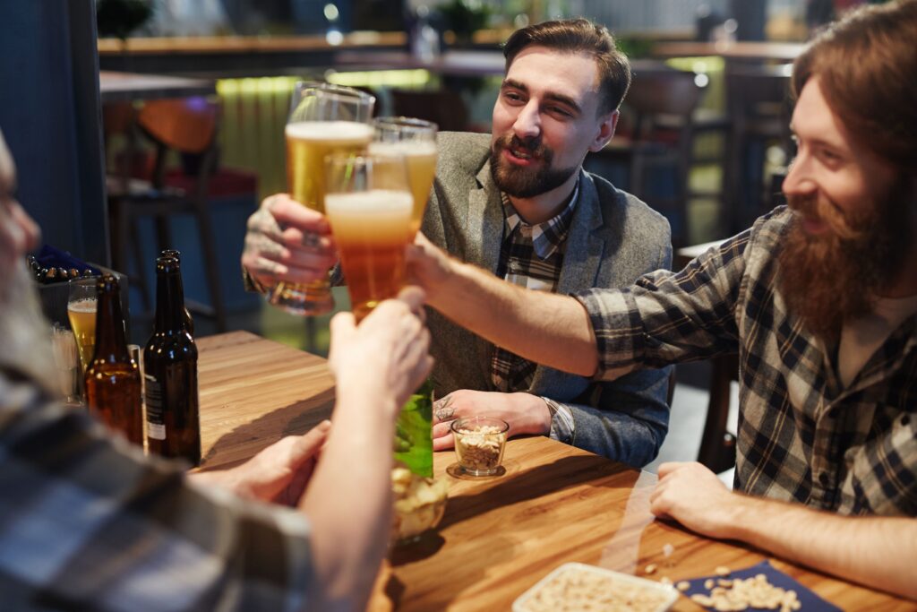 Group of friends toasting with beer glasses while celebrating at a pub.