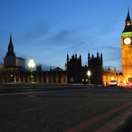 Night view of Big Ben and the Palace of Westminster with illuminated city lights and moving traffic.